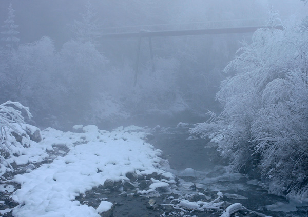 Brücke im Winter über einem Bachbett mit Schnee