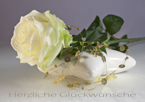 Weisse Rose liegend auf einem Glasstern, Text "Herzliche Glückwünsche"